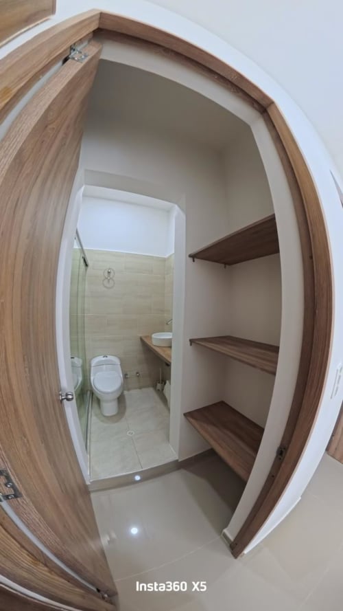 Baño con ducha de cristal y estantes de madera empotrados en el hotel Olamar Living de Santiago de Tolú
