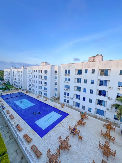 Vista aérea del hotel Olamar Living en Coveñas con edificios blancos, piscina azul y terraza arenosa
