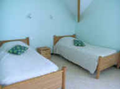 Twin beds with green pillows in Room 3 at Au Coeur des Champs B&B, Regniowez, featuring wooden frames and light blue walls