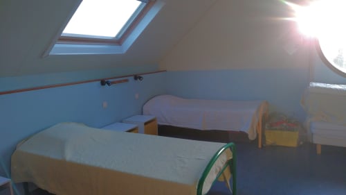 Bright attic bedroom at Au Coeur des Champs with two beds, skylight, blue walls, and garden view