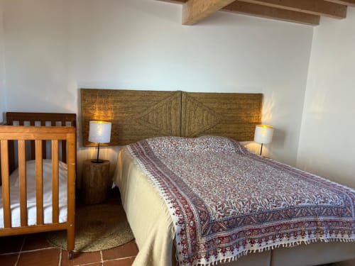 Quarto com cabeceira de madeira, colcha estampada, berço e criados-mudo na villa Casas de Juromenha em Marvão, Portugal