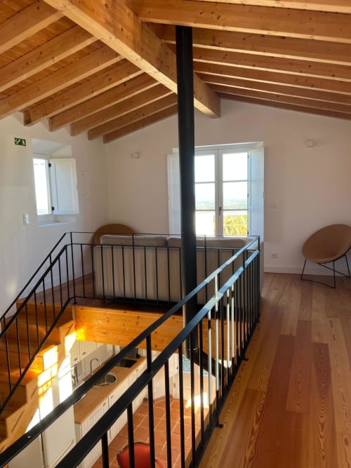 Sofisticado loft com mezanino, vigas de madeira aparente, guarda-corpos de ferro preto e vistas do vale na villa Casa dos Queixos em Marvão