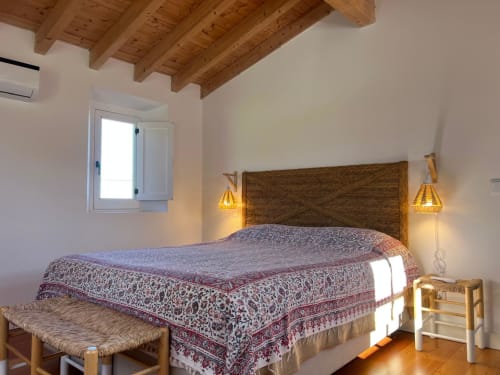 Quarto rústico na vila Casa dos Queixos em Marvão com vigas de madeira, colcha padronizada e luminárias pendentes douradas