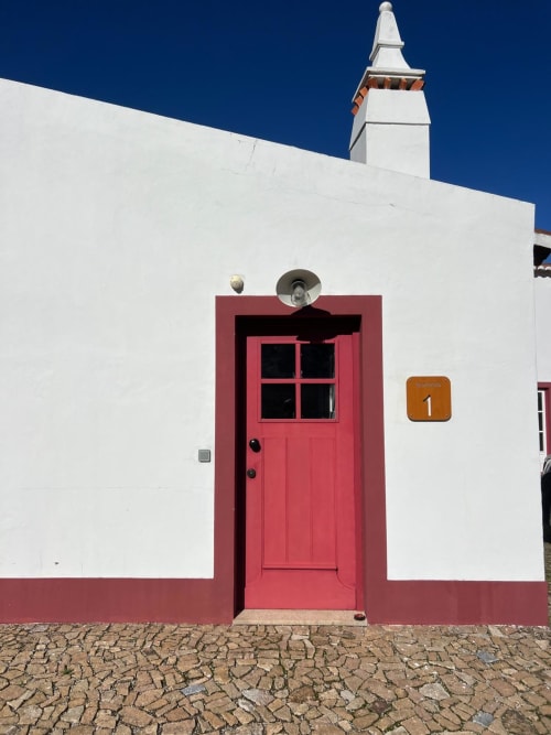 Porta vermelha de entrada da villa Casas de Juromenha em Juromenha, Portugal com paredes brancas e céu azul cristalino