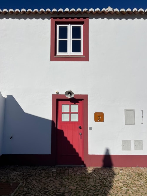 Fachada tradicional portuguesa vermelha e branca das Casas de Juromenha, Marvão, com porta e janela vermelhas