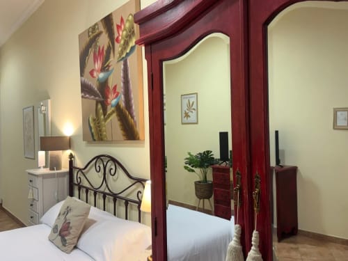 Dormitorio del apartamento Vermello en Baiona con cama de hierro forjado, armario rojo, obras de arte y vistas a la ciudad