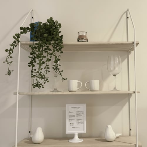 Estantería minimalista en el apartamento Holibai de Baiona con maceta, cristalería y decoración cerámica blanca