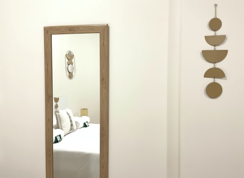 Espejo moderno de dormitorio reflejando cama con almohadas en apartamento Holibai, Baiona, con decoración de fases lunares en madera