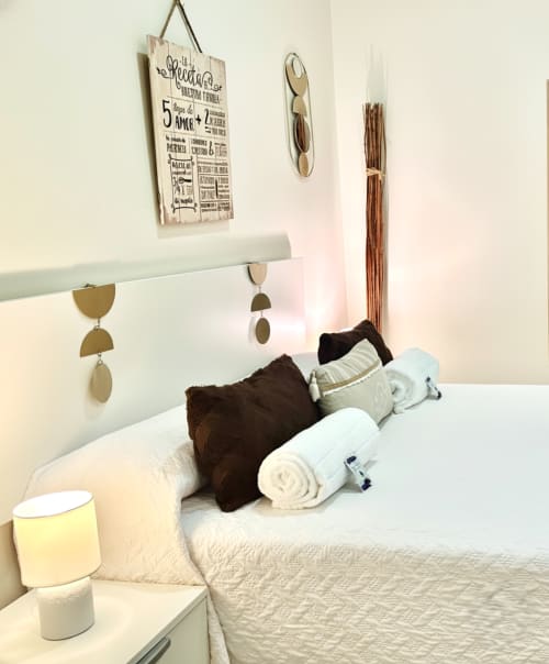 Dormitorio del apartamento Holibai en Baiona con cama blanca, almohadas marrones, toallas enrolladas y decoraciones murales