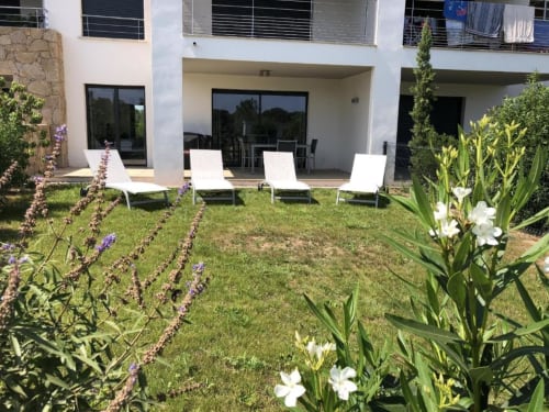 Sweet Holiday cottage garden in Porto-Vecchio with white loungers, flowering plants, and modern terrace