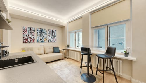 Bright living room with bar seating & city views, decorated with original art by Ralf Sannikov. Cozy studio in Tartu center near Raekoja Square. WiFi, AC, MyFitness gym & RIMI next door