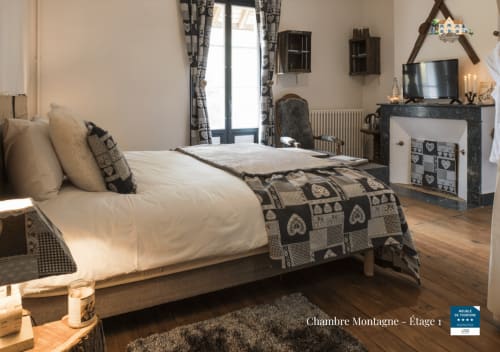 Mountain bedroom at Baccara Lodge, a 4-star B&B in Arengosse, France, featuring a bed with patterned blanket and fireplace.