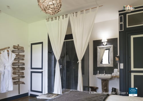 Baccara Lodge bedroom with cream curtains, black-framed door, ornate mirror, and woven pendant light in Arengosse