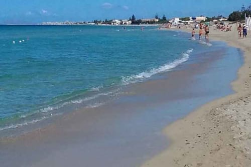 Spiaggia sabbiosa con acque turchesi e bagnanti a Marsala, Italia, vicino a Altavilla Boutique Holidays House