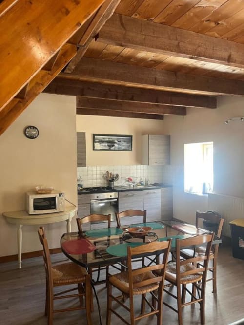 Cuisine ouverte et salle à manger de la villa Le Gîte au Manoir de Fornebello avec poutres apparentes, table et équipements