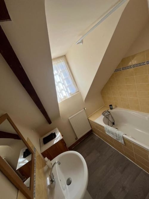 Salle de bain moderne de la villa Le Gîte au Manoir de Fornebello avec lavabo, baignoire et puits de lumière naturel