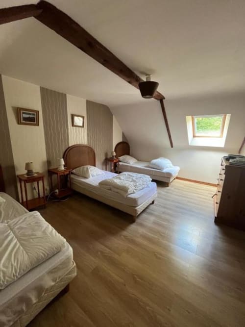 Chambre spacieuse du Manoir de Fornebello avec trois lits simples, poutres apparentes, lucarne et mobilier d'époque