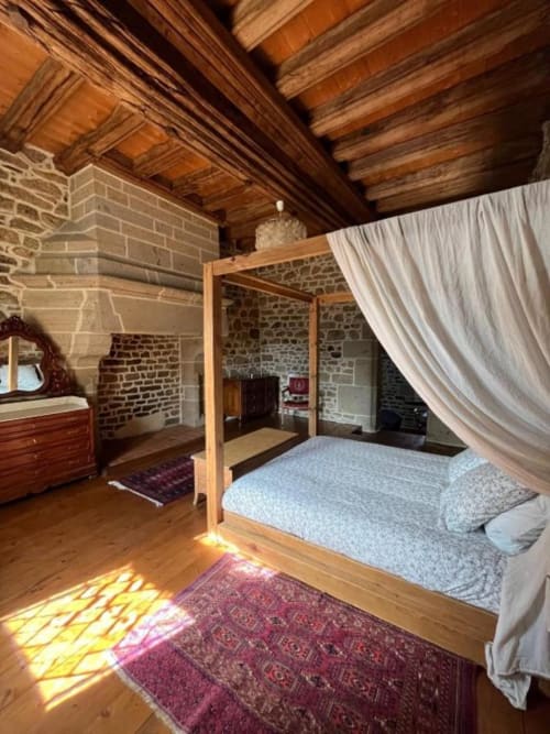 Lit à quatre colonnes luxueux dans la suite en pierre du Manoir de Fornebello, avec poutres, cheminée et vue sur le jardin