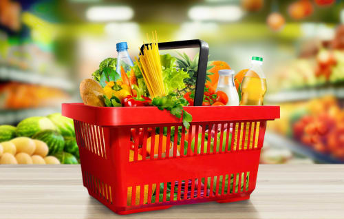 Red shopping basket filled with groceries and fresh produce in grocery store at Sweet Holiday hotel Porto-Vecchio