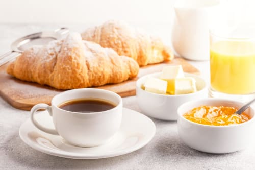 Continental breakfast spread at Sweet Holiday hotel in Porto-Vecchio with croissants, coffee, orange juice, butter and jam