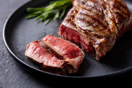 Medium-rare steak slices with rosemary on black plate at Sweet Holiday hotel, Porto-Vecchio