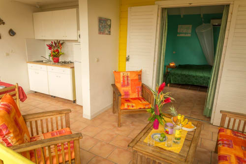 La jolie terrasse du gîte BleuLagon, avec d'un côté la cuisine équipée et de l'autre l'espace détente, aux couleurs créoles, pour des vacances réussies aux Jardins de l'espérance à Bouillante en Guadeloupe