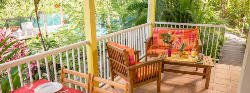 La belle terrasse colorée du gîte VertMadras, vue sur la piscine sécurisée et le jardin paysager des jardins de l'espérance à Bouillante, pour de belles vacances en famille