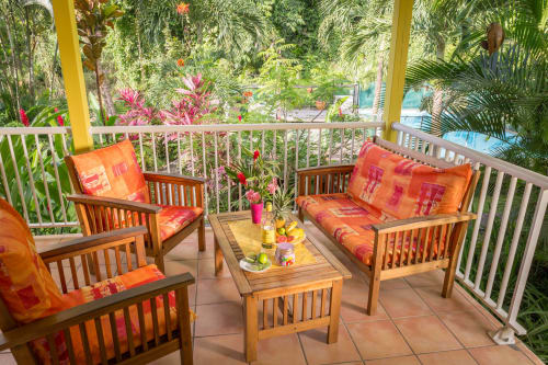 Belle terrasse colorée du gîte VertMadras pour 2 à 4 personnes aux jardins de l'espérance à Bouillante en Guadeloupe, avec une très jolie vue sur la piscine sécurisée et le jardin tropical fleuri