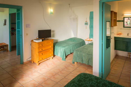 la grande chambre familiale climatisée du gîte Mussaenda aux jardins de l'espérance à Bouillante en Guadeloupe, avec un lit de 160cm et 2 lits simples 90cm et sa salle de bains privative 