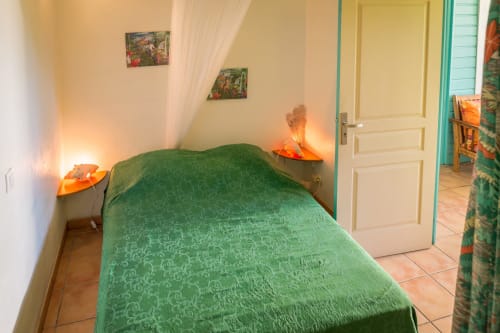 la petite chambre climatisée du gîte Mussaenda, avec sa salle de bain privative, lit de 140cm et moustiquaire, espace de rangement. C'est aux jardins de l'espérance à Bouillante en Guadeloupe