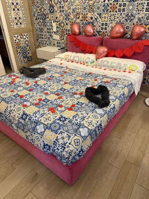 Camera romantica della San Nicola Suite Mini Apartments a Sorrento con biancheria decorata, ornamenti a cuore e piastrelle ornate