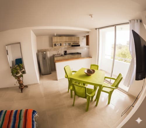 Luminosa sala de estar en Olamar Living con mesa de comedor verde, cocina y terraza con vistas al jardín