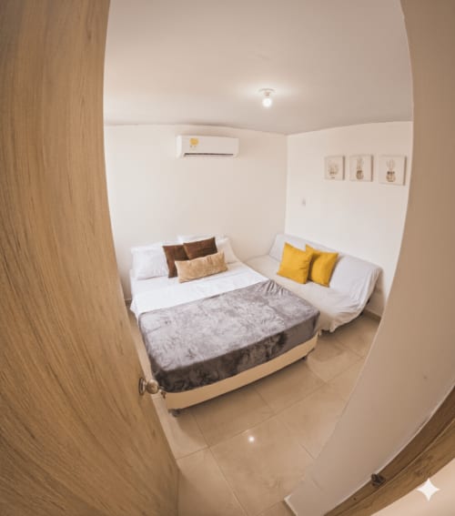 Luminosa habitación doble en hotel Olamar Living de Santiago de Tolú con camas gemelas, almohadas amarillas, aire acondicionado y diseño moderno