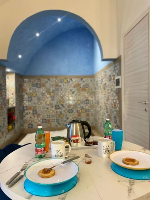 Colazione in camera d'albergo a Sorrento con soffitto a cupola blu, pasticcini in piatto e servizi colorati