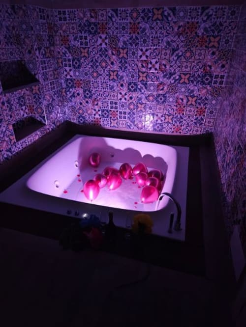 Vasca da bagno lussuosa illuminata con petali di rosa rosa presso la San Nicola Suite Mini Apartments a Sorrento
