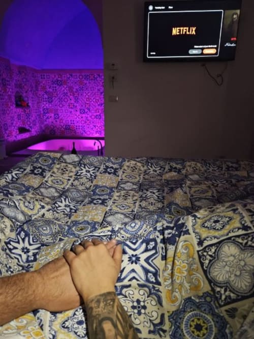 Camera accogliente della San Nicola Suite a Sorrento con illuminazione al neon viola, biancheria a motivi e Netflix sulla TV a parete