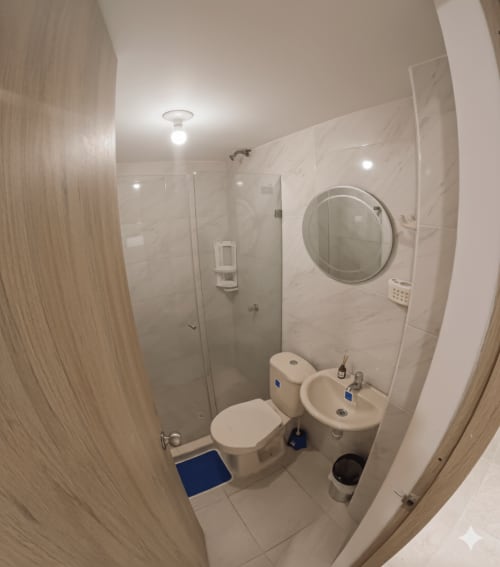 Baño moderno del hotel Olamar Living en Santiago de Tolú con inodoro, lavamanos, espejo y ducha de acceso directo