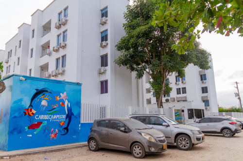Edificio residencial Olamar en Santiago de Tolú con autos estacionados y colorido mural caribeño