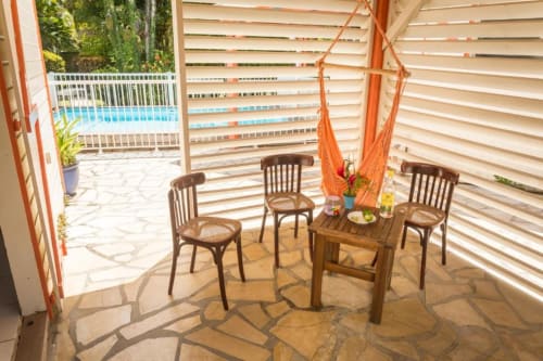 La jolie petite terrasse de l'hébergement Bougainvilliers, aux jardins de Pointe Noire, en Guadeloupe, devant la piscine sécurisée de la résidence de vacances