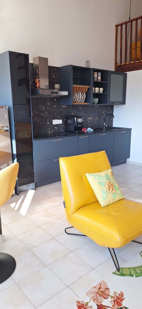 Modern kitchen with yellow chair in Mana Bleu apartment, managed by Corsu di Core