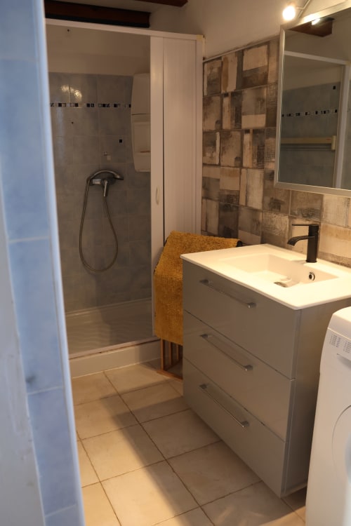Modern bathroom in Mana Bleu apartment with white vanity, walk-in shower, and heated towel rack in Favone, managed by Corsu di Core