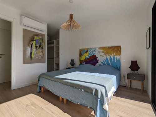 Modern bedroom in villa with colorful headboard, wooden pendant light, and contemporary decor in Favone, managed by Corsu di Core