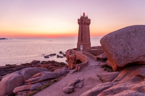 Phare rouge au coucher de soleil avec rochers de granit sur la côte bretonne près de Châtelaudren-Plouagat, France
