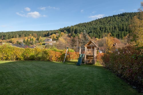 Ein Kinderspielplatz befindet sich in einem sicheren und absolut ruhigen Garten mit herrlichem, unverbautem Blick auf Wald und Berge. Dieser private Außenbereich ermöglicht es den Kleinen, sicher zu spielen, während die Eltern die Ruhe und die umliegende Natur genießen. Der Garten ist ideal für Familienurlaube und bietet mit Grünflächen, Spielgeräten und Panoramablick in die Natur eine wahre Oase der Entspannung.