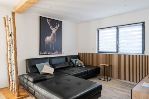 Großzügiges, offenes Wohnzimmer im natürlichen und industriellen Stil.
Das geräumige, tiefe Panorama-Ecksofa aus schwarzem Leder lädt zum Entspannen vor dem großen OLED-Fernseher ein.

Ein gemütlicher und einladender Wohnbereich, ideal für gesellige Stunden mit Familie und Freunden.