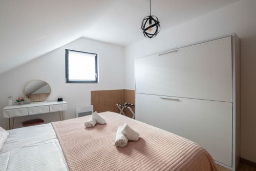 Charmantes Zimmer mit Kingsize-Bett, ideal für bis zu vier Personen. Ein ausziehbares Etagenbett bietet zusätzlichen Schlafplatz und maximiert die Kapazität. Die helle, moderne Einrichtung sorgt für eine warme und behagliche Atmosphäre.

Ein eleganter weißer Schminktisch trägt zu einem angenehmen und praktischen Aufenthalt bei.