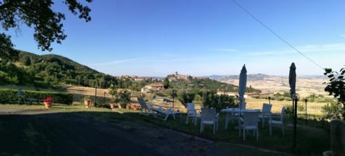 Vista sulla campagna toscana dal patio di I Castagnini B&B con sedie bianche e ombrelloni che si affacciano sulle colline ondulate