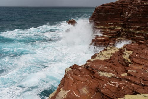 Dramatic red rock cliffs meet turquoise waves at Terrasini coastal property Case Zucco