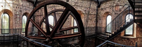 Grande ruota di mulino in ferro arrugginito nell'edificio storico in laterizio di I Castagnini B&B, Montecatini Val di Cecina, Italia
