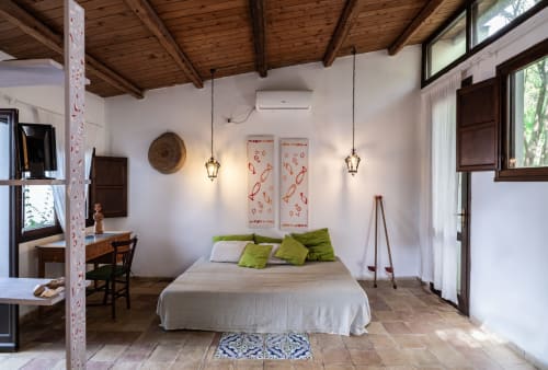 Bright bedroom at Case Zucco B&B in Terrasini with white walls, exposed wooden beams, green accent pillows, and hanging